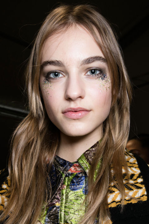 Inspired by the electric colors and metallic embroidery of the Fall collection, makeup artist Wendy Rowe and her team applied 3,000 glitter flecks under the eyes backstage at Burberry for a post-festival vibe.<br />