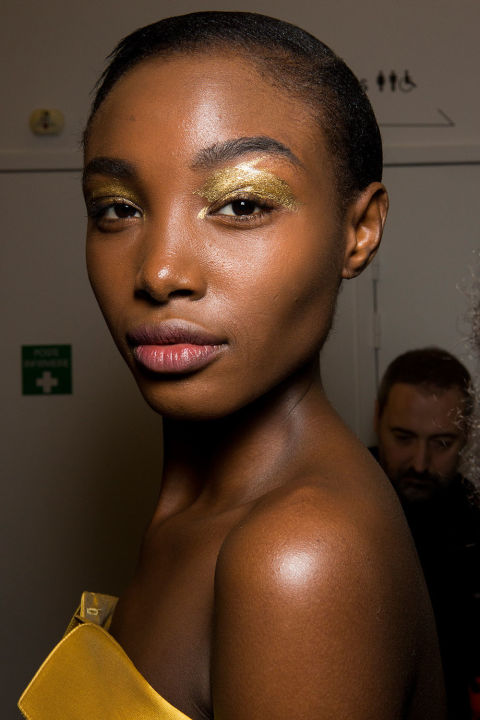 This season is all about touches of metallics: a little silver swept under the eye, a little copper pressed on the center of the lid. At Alexis Mabille, gold was the element du jour, and it carried all the way down on the runway from the eyes to the foiled gold boots. Makeup artist Lloyd Simmons painted a gold pigment across the models' eyelids in a brushstroke pattern. The rest of the face we left bare. The eyes were only matched in shine-factor by the gold chrome nails.